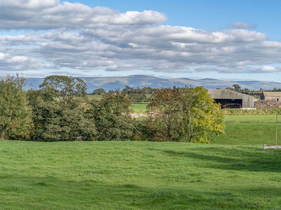 A landscape with trees and a farm building near mountains at Cosy cottage near scenic walks and country pub, Penrith