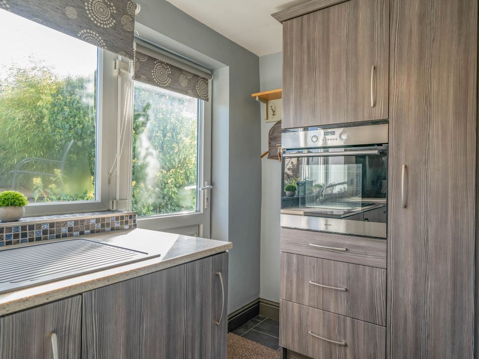 A kitchen with a window and oven at Cosy cottage near scenic walks and country pub in Penrith