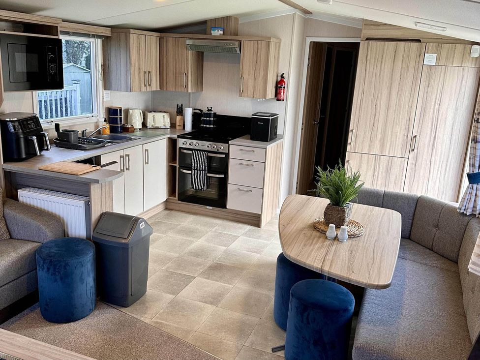 A kitchen with appliances and seating at R&R Coastal Retreats Cedars 63 Skegness