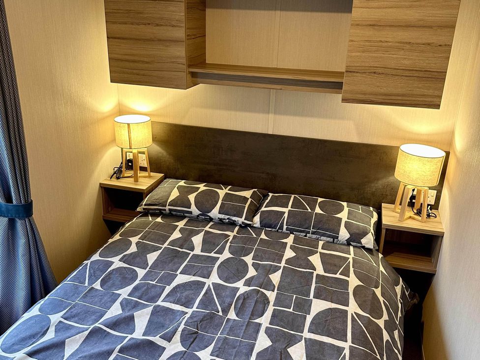 A bedroom with a bed and lamps at R&R Coastal Retreats Cedars 63 in Skegness