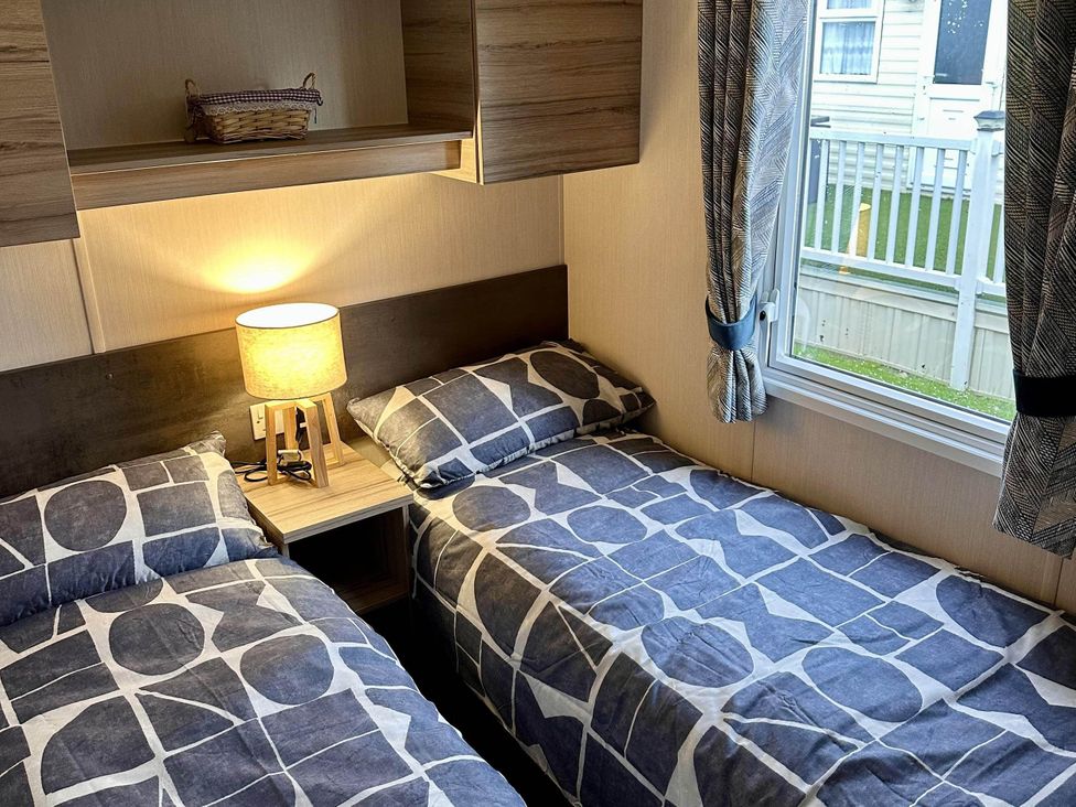 A bedroom with two beds and a lamp at R&R Coastal Retreats Cedars 63 in Skegness