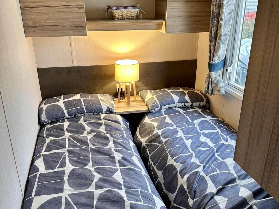 A bedroom with two single beds and a lamp at R&R Coastal Retreats Cedars 63 in Skegness
