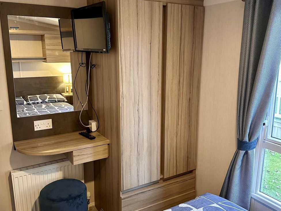 A bedroom with a wardrobe and television at R&R Coastal Retreats Cedars 63, Skegness