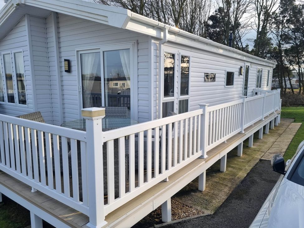 An outdoor view of a lodge with a wooden deck at Cayton Bay Lodge Parkdean Resorts Scarborough