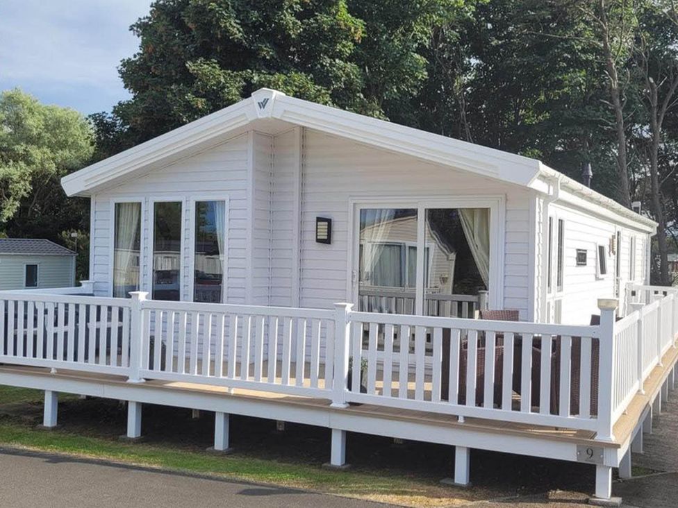 A mobile home with decking and outdoor furniture at Cayton Bay Lodge Parkdean Resorts in Scarborough