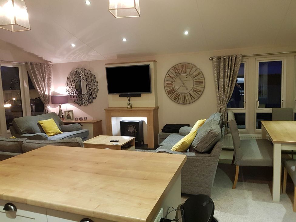 A living room with a sofa, television, and dining table at Cayton Bay Lodge Parkdean Resorts, Scarborough