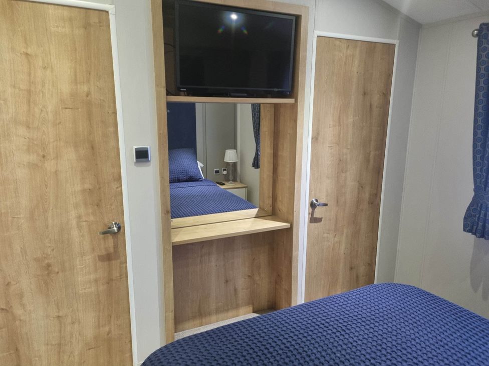 A bedroom with a television and lamp at Cayton Bay Lodge Parkdean Resorts, Scarborough