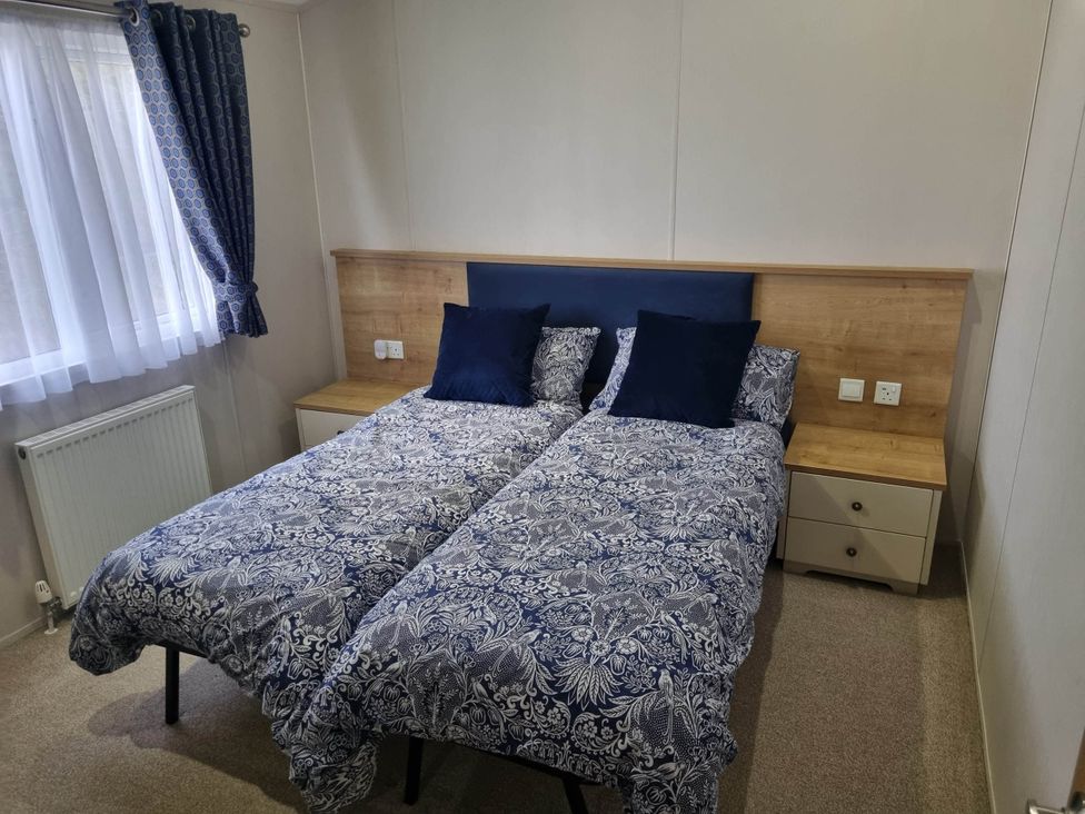 A bedroom with two beds and a bedside table at Cayton Bay Lodge Parkdean Resorts in Scarborough