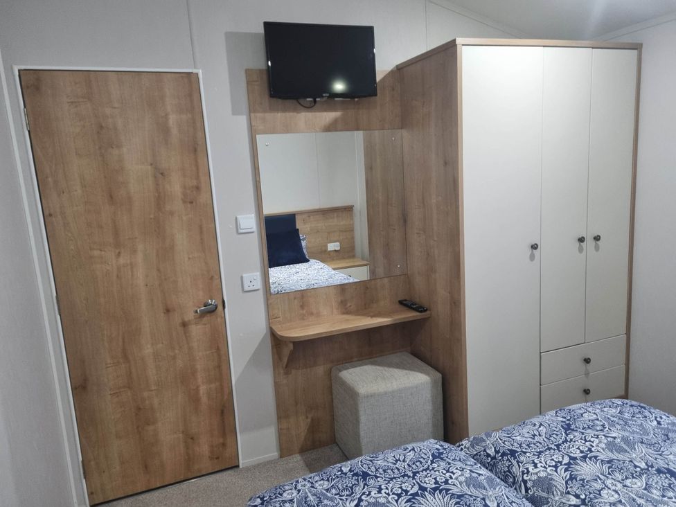 A bedroom with a bed, TV, and wardrobe at Cayton Bay Lodge Parkdean Resorts, Scarborough