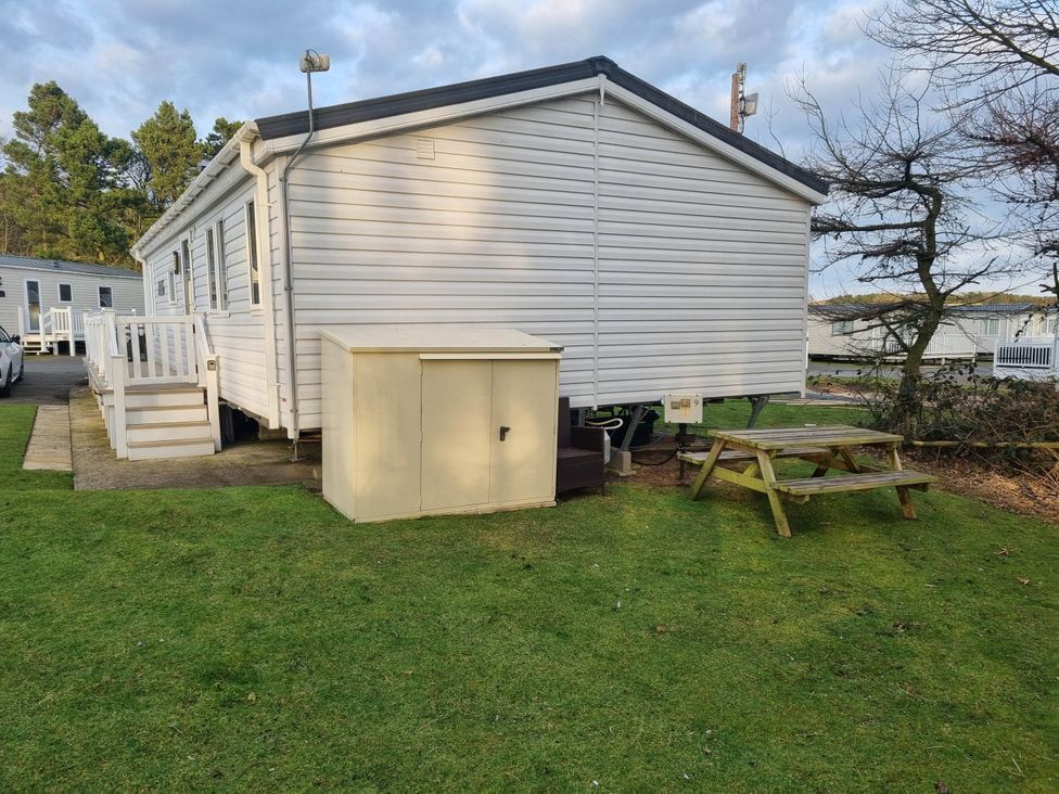 A caravan with a picnic table and storage shed at Cayton Bay Lodge Parkdean Resorts Scarborough
