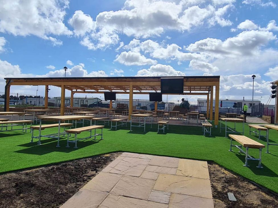 An outdoor area with tables and benches under a canopy at Cayton Bay Lodge Parkdean Resorts, Scarborough