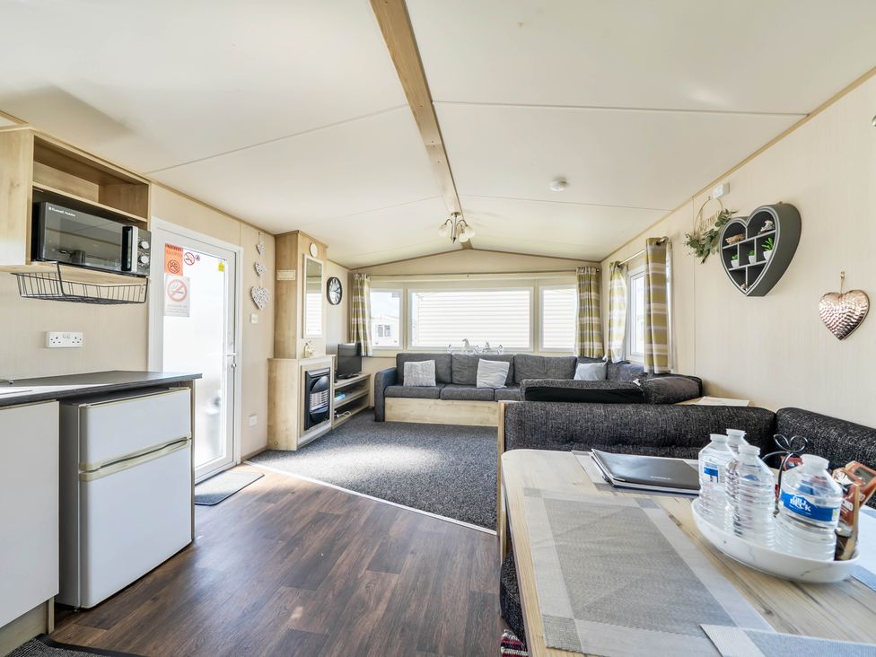A living room with a sofa and table at Sleeps 8 Communal Spa Access Parking Rhyl