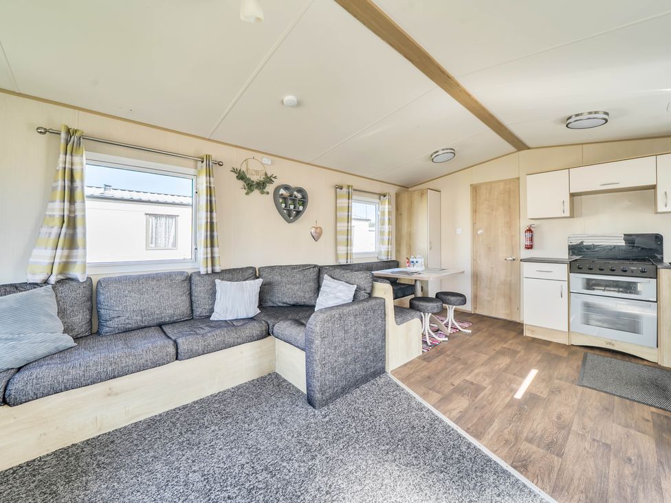 A living room with a sofa and kitchen unit at Sleeps 8 Communal Spa Access Parking Rhyl