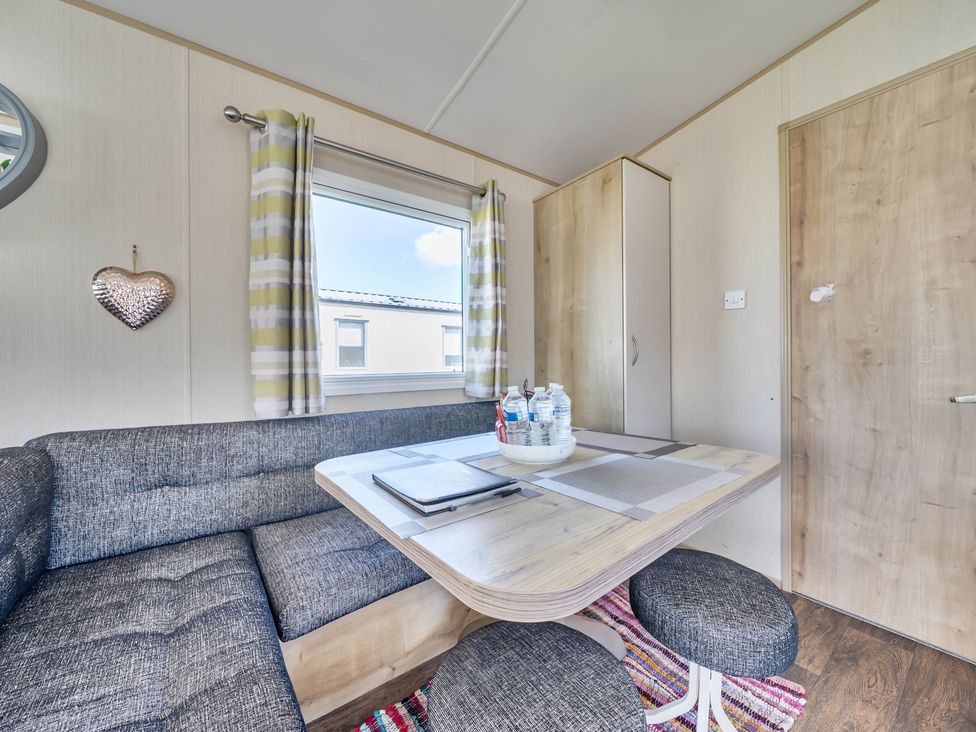 A dining area with a table and sofa at Sleeps 8 Communal Spa Access Parking in Rhyl
