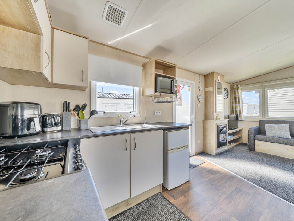 A kitchen with appliances and seating area at Sleeps 8 Communal Spa Access Parking Rhyl