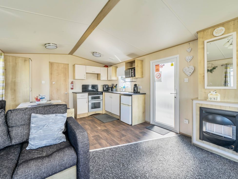 A kitchen with a sofa and appliances at Sleeps 8 Communal Spa Access Parking in Rhyl