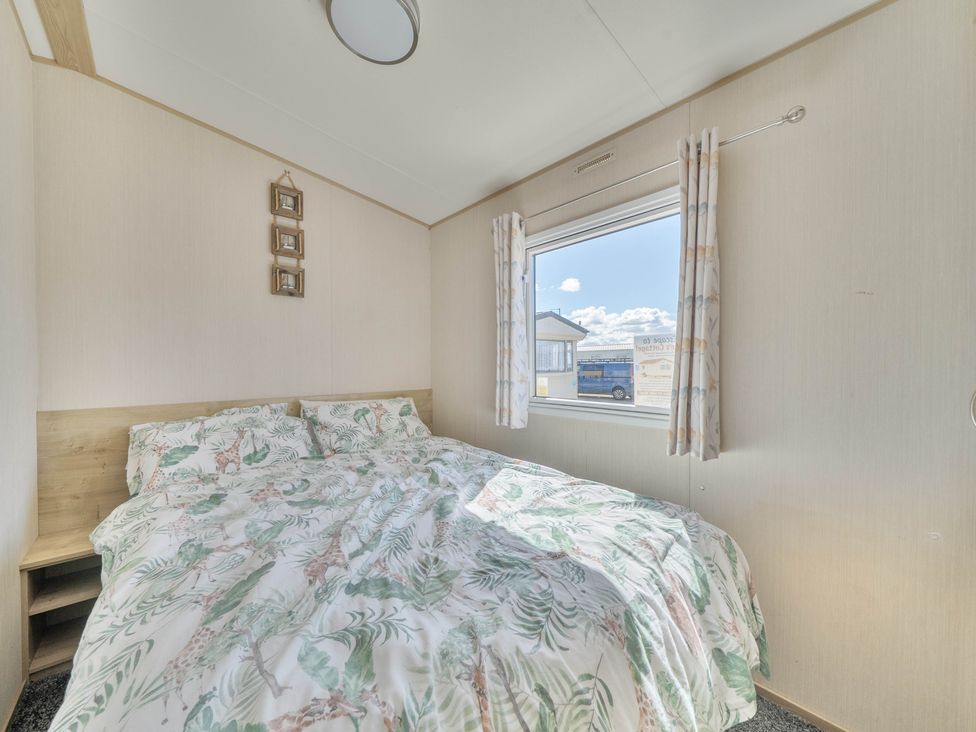 A bedroom with a bed and window at Sleeps 8 Communal Spa Access Parking Rhyl