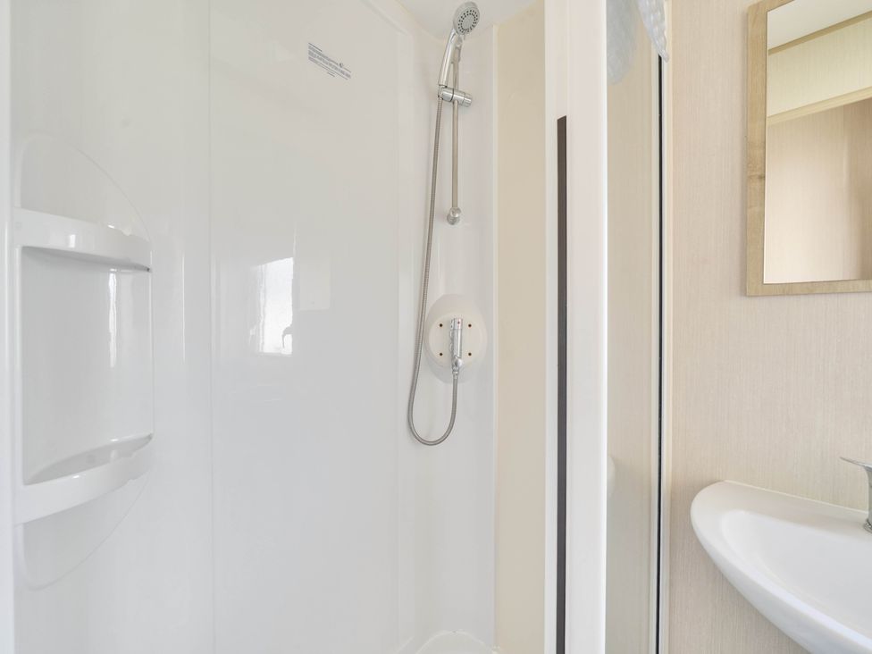 A shower with a sink and mirror in the bathroom at Sleeps 8 Communal Spa Access Parking Rhyl