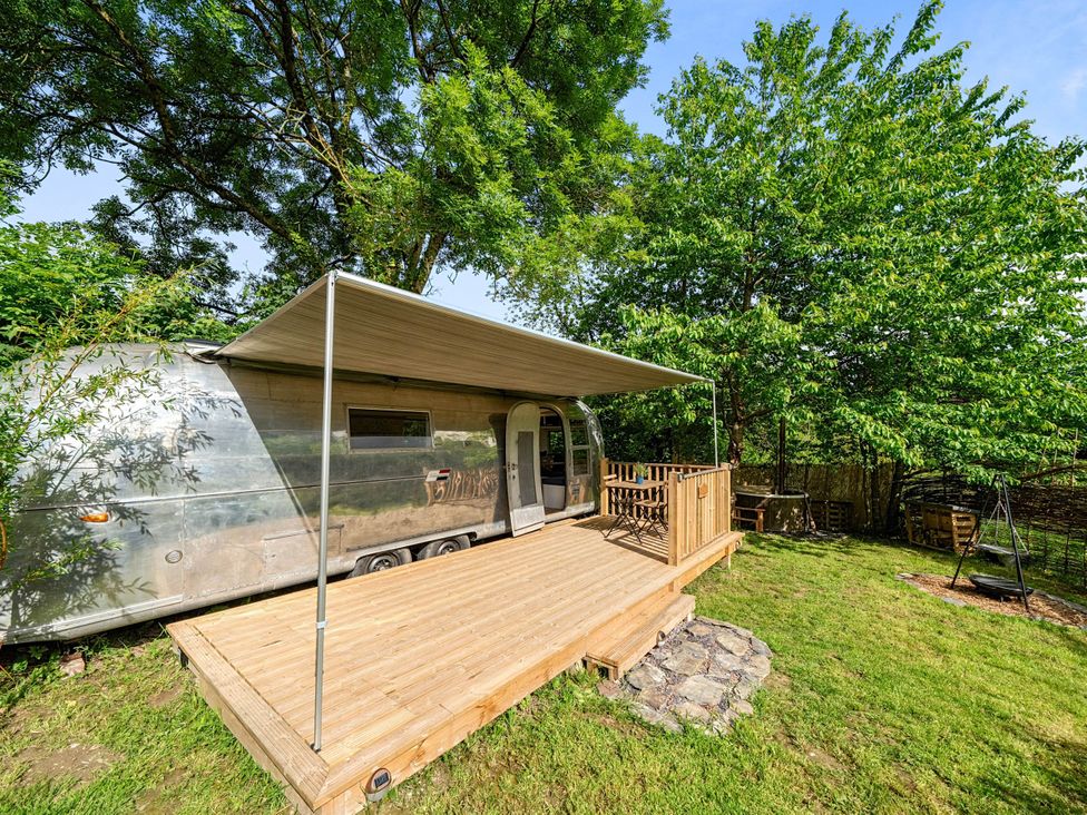 A trailer with a deck in a garden at Sleeps 2 - Private Hot Tub - Fire Pit in St. Dogmaels near Cardigan