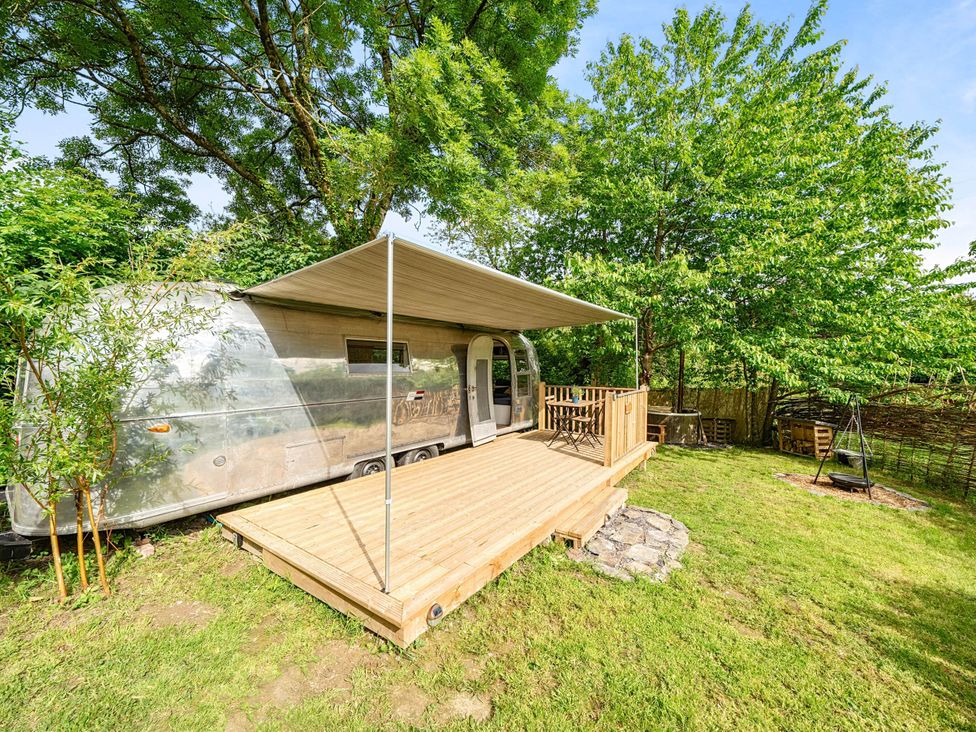 A trailer on a wooden deck surrounded by grass and trees at Sleeps 2 - Private Hot Tub - Fire Pit in St. Dogmaels near Cardigan