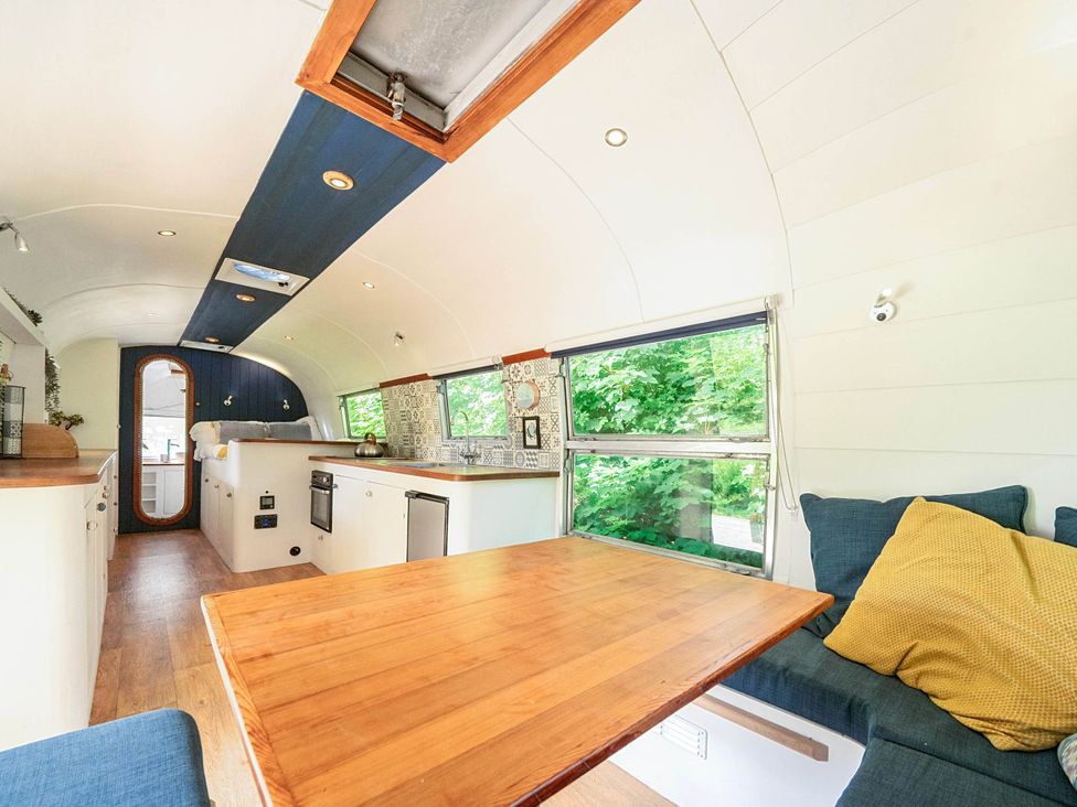 A living area with a table and sofa in a converted bus at Sleeps 2 - Private Hot Tub - Fire Pit, St. Dogmaels near Cardigan