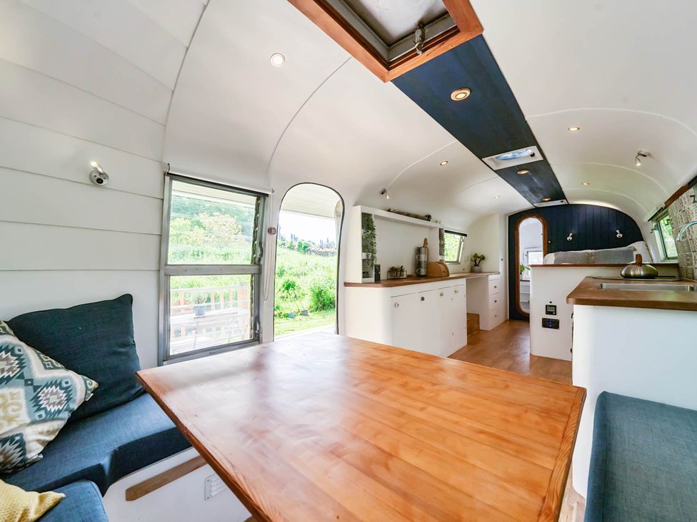 A living room with a table and couch at Sleeps 2 - Private Hot Tub - Fire Pit, St. Dogmaels near Cardigan