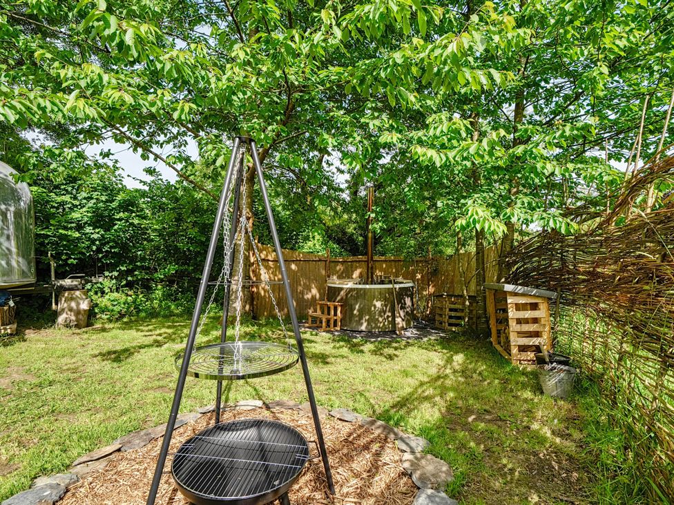 A garden with a hot tub and grill at Sleeps 2 - Private Hot Tub - Fire Pit in St. Dogmaels near Cardigan