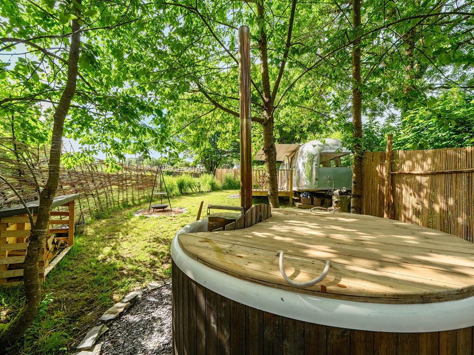 A garden with a hot tub and swing at Sleeps 2 - Private Hot Tub - Fire Pit, St. Dogmaels near Cardigan