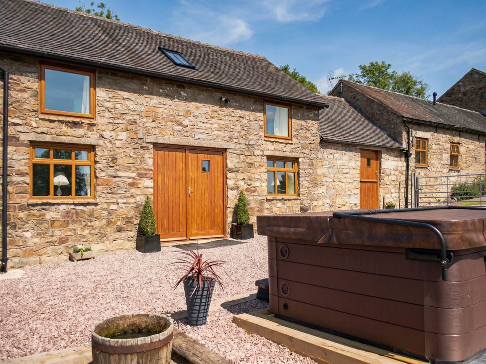 An outdoor area with a stone building and a hot tub in front at a rural property