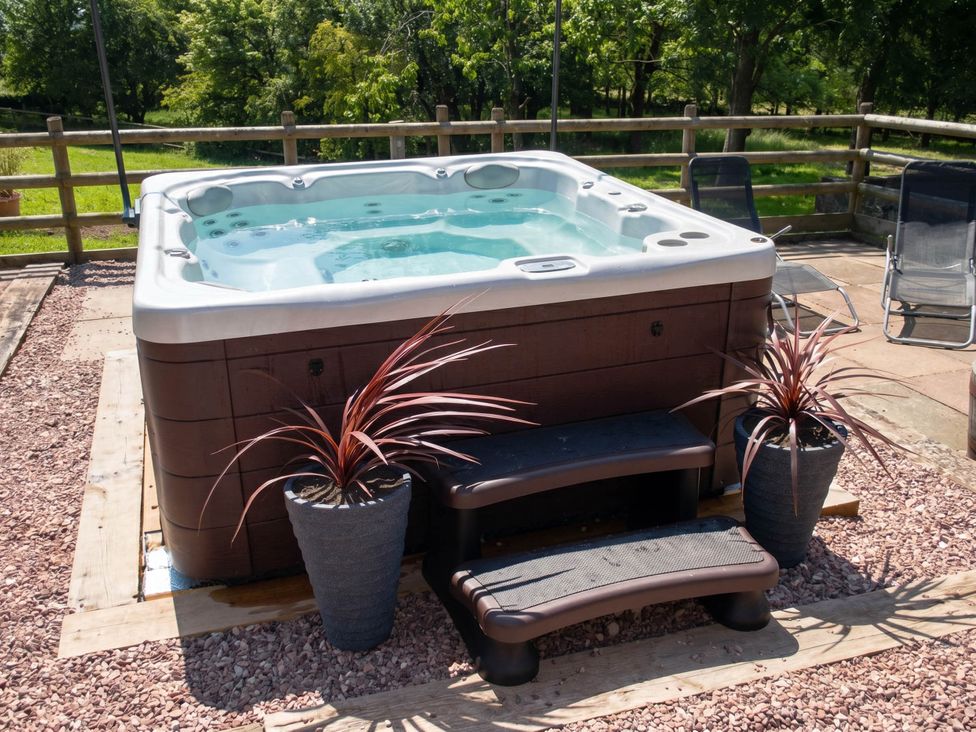 A hot tub with steps and planters in a yard
