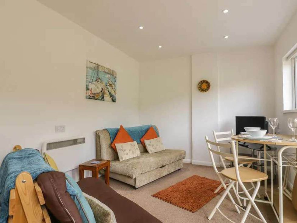 A living room with a sofa and dining area at Bungalow Sleeps 2 Parking in Newquay
