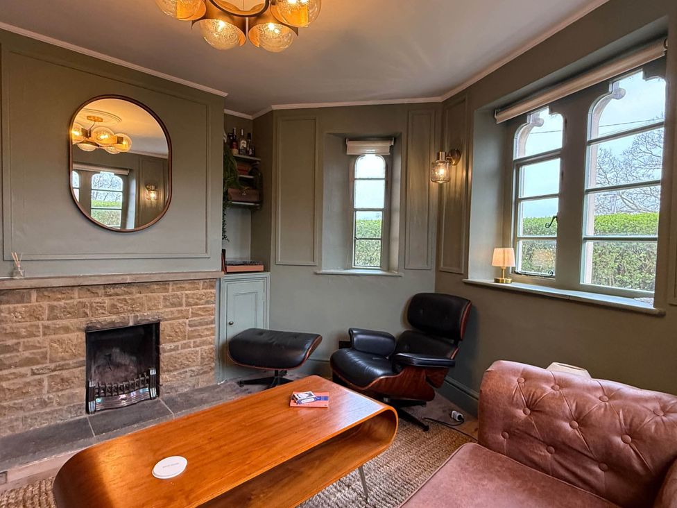 A living room with a fireplace and armchair at Cotswolds Castle Sleeps 8 with Enclosed Garden in Banbury