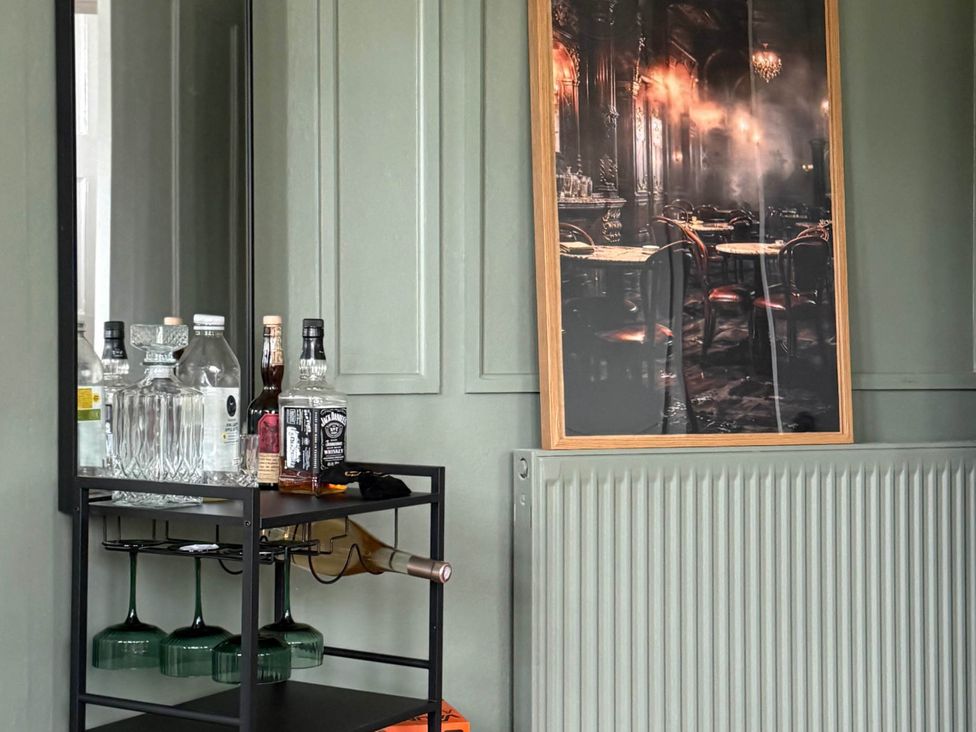A bar cart with bottles and a mirror in a living room at Cotswolds Castle Sleeps 8 with Enclosed Garden Banbury
