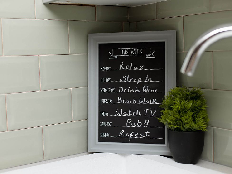 A chalkboard with a weekly schedule and a small plant in a kitchen