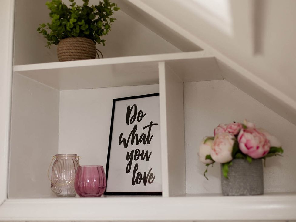 A shelf with a plant, picture frame, and decorative glass containers at Cottage Sleeps4 PetFriendly Garden ByBeach in Lytham St Annes