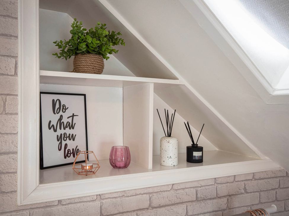 A shelf with a plant, framed print, candle holder, and diffusers at Cottage Sleeps4  PetFriendly  Garden  ByBeach in Lytham St Annes