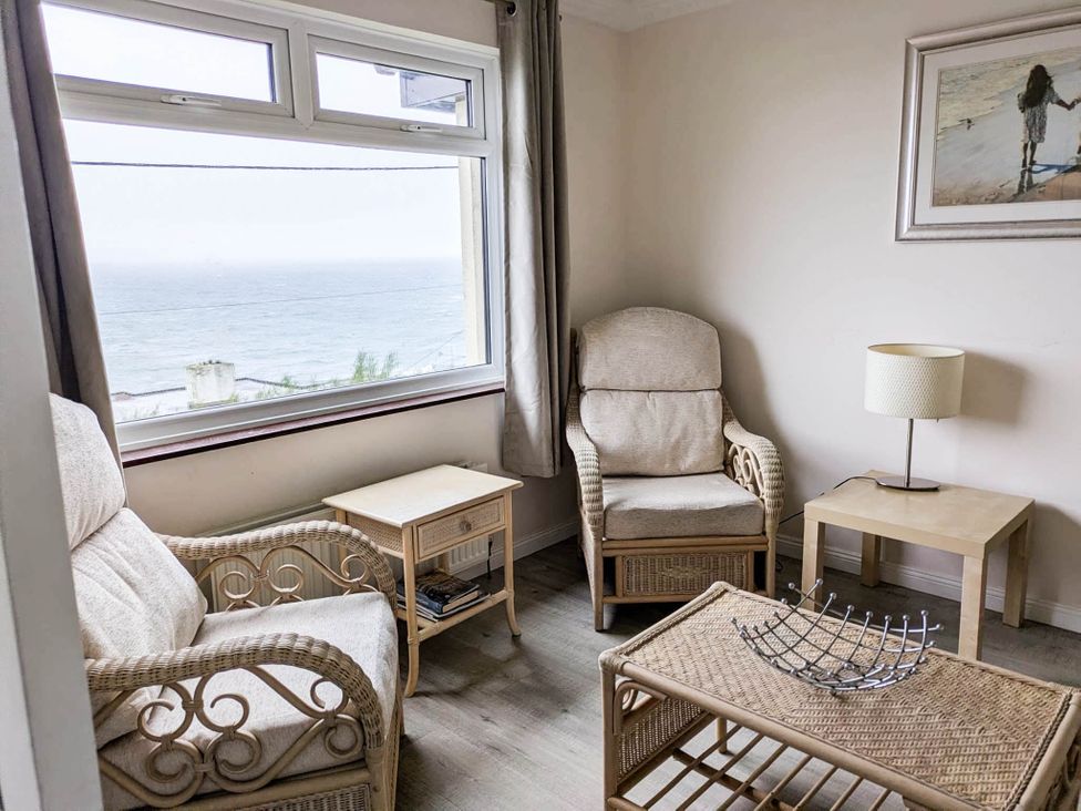 A living room with rattan furniture and a view of the sea at Porthleven Coastal Retreat with 5 Bedrooms Porthleven