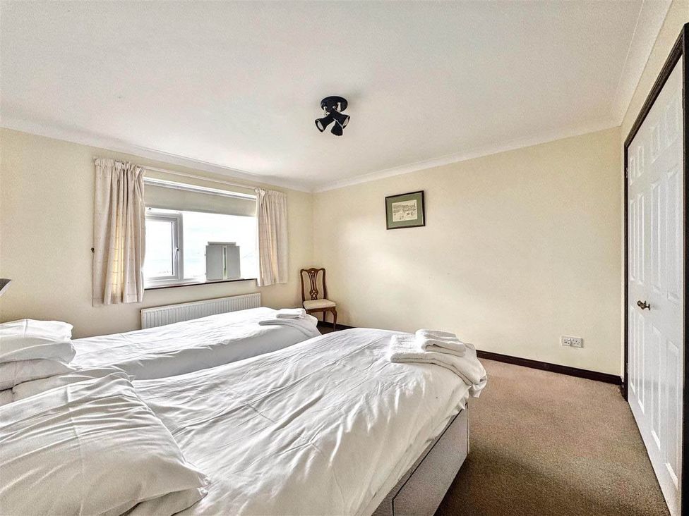 A bedroom with two beds and a chair at Porthleven Coastal Retreat with 5 Bedrooms, Porthleven