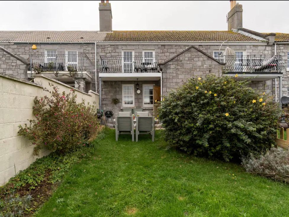 A garden with chairs and a bush at Beautiful Sea Front Cottage in Plymouth