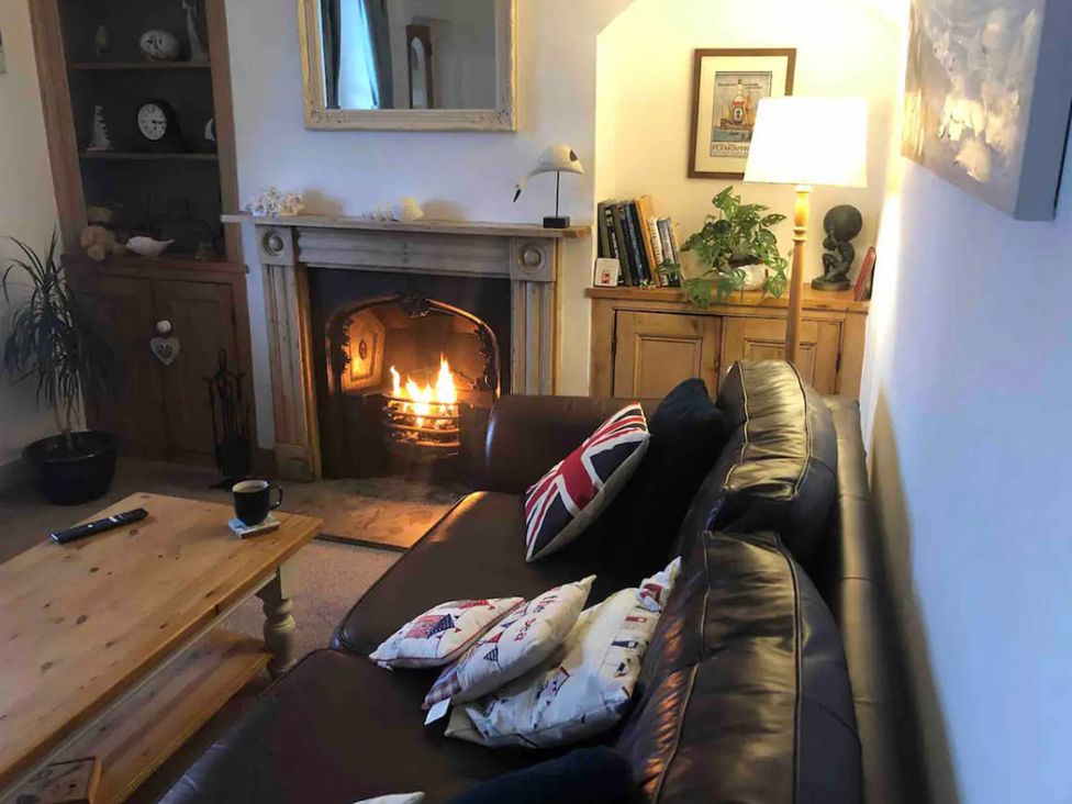 A living room with a fireplace and a sofa at Beautiful Sea Front Cottage in Plymouth