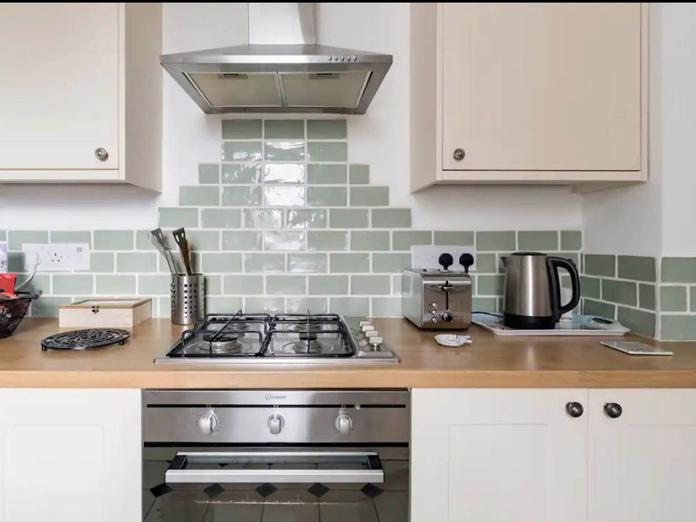 A kitchen with a stove, kettle, toaster, and storage at Beautiful Sea Front Cottage in Plymouth