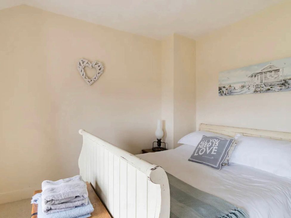 A bedroom with a bed and towels stacked in the Beautiful Sea Front Cottage in the Ocean City, Plymouth
