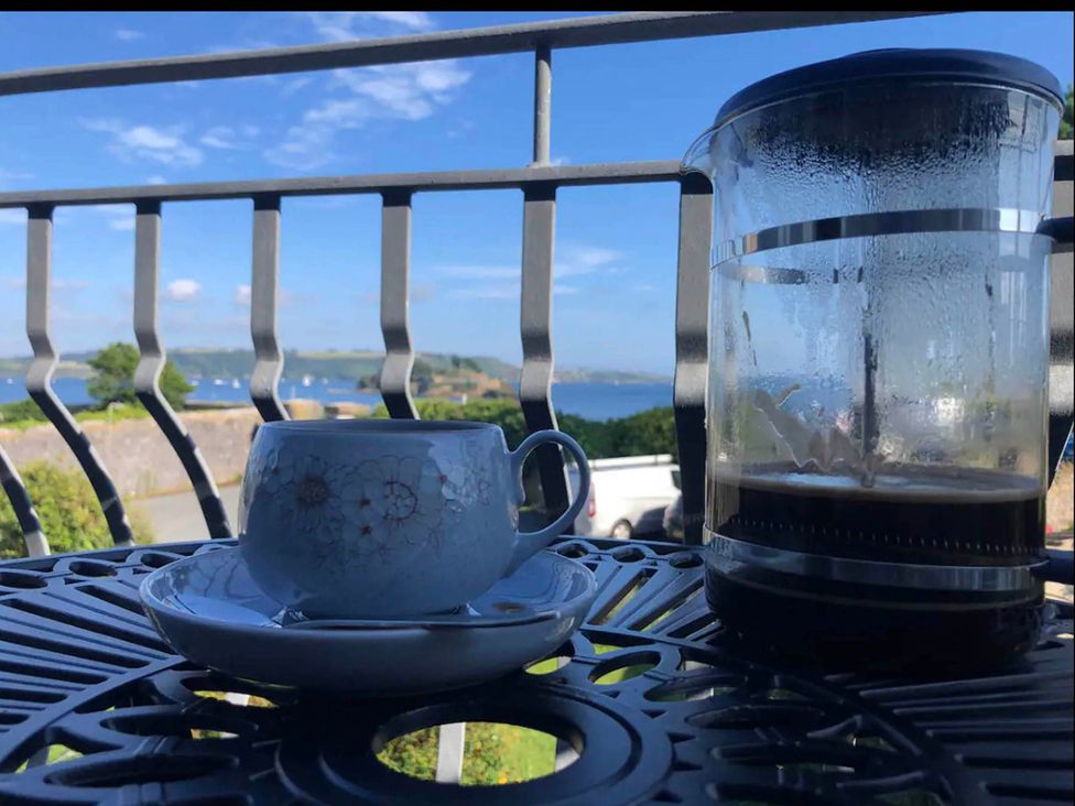 A cup and a french press on a table with an ocean view at Beautiful Sea Front Cottage in Plymouth