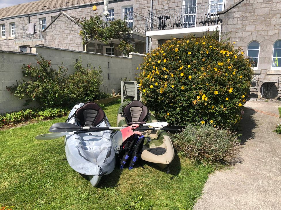 A garden with kayaks and paddles in front of a bush at Beautiful Sea Front Cottage in Plymouth