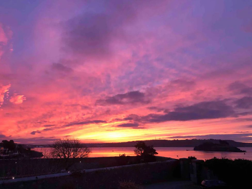 A sunset view over the water with trees and an island at Beautiful Sea Front Cottage in Plymouth