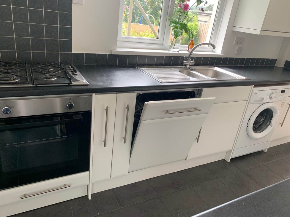 A kitchen with a gas stove, oven, dishwasher and washing machine at 2 Bed Sleeps 4 Parking Pets 10 min walk to Beach in Falmouth