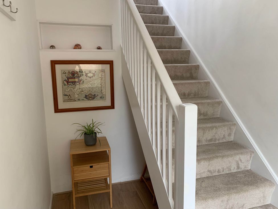 A hallway with stairs, a painting and a table at 2 Bed Sleeps 4 Parking Pets 10 min walk to Beach Falmouth