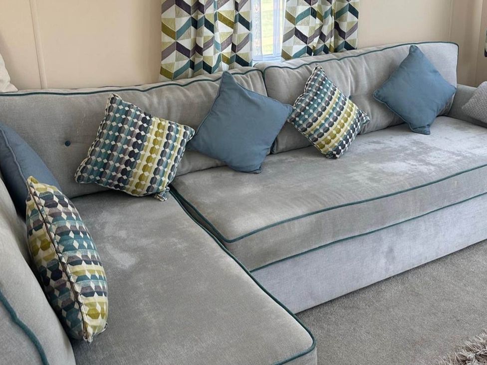 A sofa with cushions in a living room at Caravan in Holcot Sleeps 6 Max 6 people Max 4 adults per booking Pet Friendly Holcot near Moulton