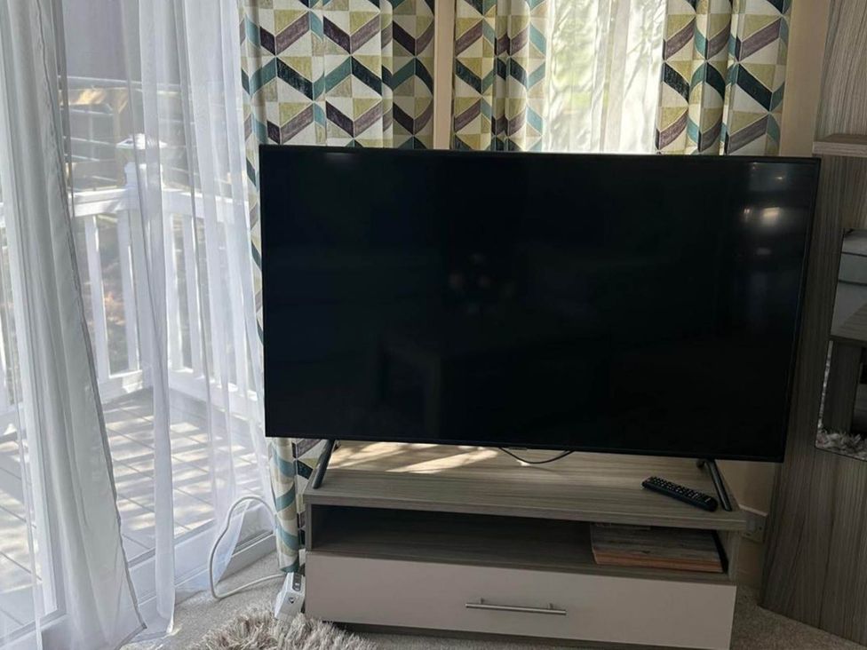 A television on a stand with a remote control in the living room at Caravan in Holcot Sleeps 6 Max 6 people Max 4 adults per booking Pet Friendly Holcot near Moulton