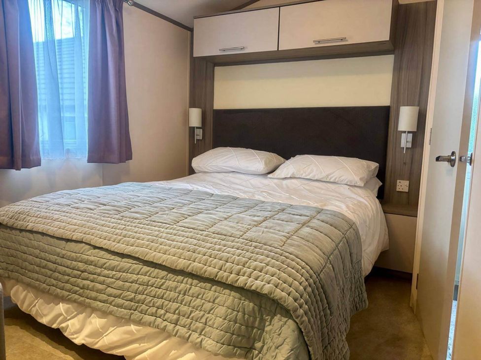 A bedroom featuring a double bed with a light green cover at Caravan in Holcot Sleeps 6 Max 6 people Max 4 adults per booking Pet Friendly Holcot near Moulton